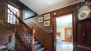 A staircase with wooden balusters and a plaid carpet, leading to a room with a large clock and framed pictures on the wall. - Balloan House-UK7383 (Dornoch)