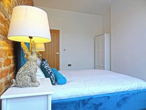 Une chambre à coucher comprenant un lit, une table de chevet avec une lampe, une commode et une armoire.