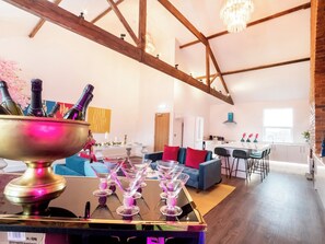 A spacious living area with a high ceiling, exposed wooden beams, a chandelier, and a dining area with a white table and chairs. - 5 bedroom accommodation in York (York)
