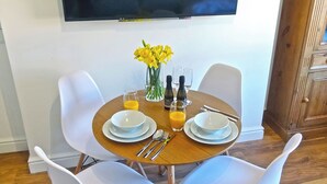 A dining table with white plates, cutlery, and a vase of yellow flowers.