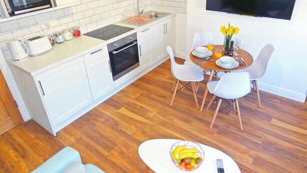 A modern kitchen with white cabinets, a built-in oven, and a dining area with a table set for two.