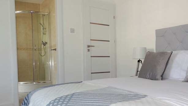 Hotelkamer met een groot bed, een douche en een deur met lichtschakelaar.