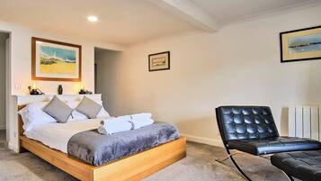 A bedroom with a wooden bed, a black leather chair, and two framed pictures on the wall.