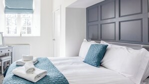 Une chambre à coucher avec un lit, une commode, une fenêtre donnant sur un beau paysage et une porte.