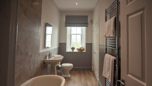 Une salle de bain équipée d’une baignoire, d’un lavabo, de toilettes et d’une fenêtre donnant sur un paysage agréable.