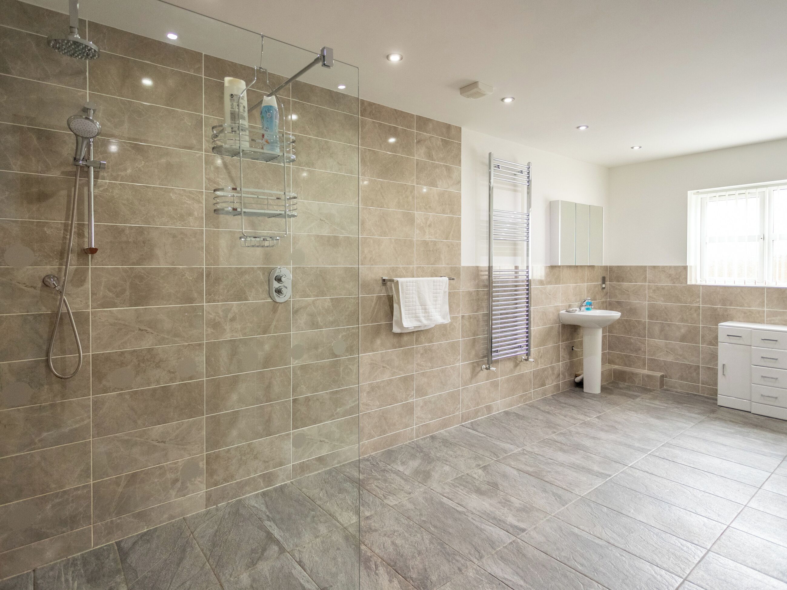 A modern bathroom with a glass shower enclosure, a built-in sink, and a towel rack.