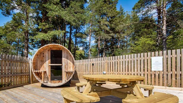 A wooden deck with a picnic table and a barrel structure.