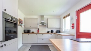 A modern kitchen with white cabinets, a microwave, a stove, and a sink.