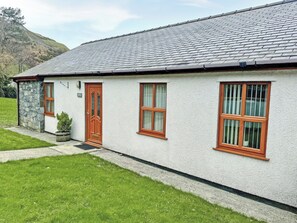 Ein zweistöckiges Haus mit einer Stein-Fassade, einer Holztür und einem Fenster mit Holzrahmen.