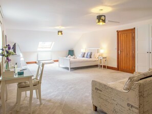 A bedroom with a bed, a desk, a chair, a lamp, a wooden wardrobe, and a window. - Willow Cottage-UK2788 (Penmaenmawr, near Conwy)