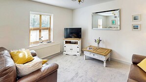 Ein Wohnzimmer mit einem braunen Ledersofa, einem weißen Schrank, einem kleinen Holztisch und einem großen Spiegel an der Wand.
