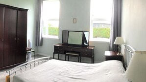 Quarto com cama, penteadeira, espelho e janela.