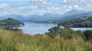 Vista panorâmica de um lago rodeado por colinas e montanhas.