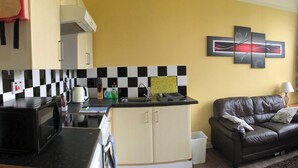 Um espaço compacto com cozinha americana, um sofá e um detalhe decorativo na parede.