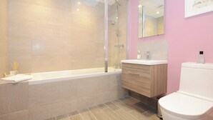 A modern bathroom with a bathtub, a shower, a vanity with a mirror, and a toilet. - 1 bedroom accommodation in York (York)