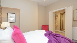 A hotel room with a bed, a lamp, a red chair, a purple blanket, and a mirror. - 1 bedroom accommodation in York (York)