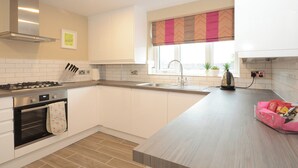 A modern kitchen with white cabinets, a stainless steel stove, and a window with a patterned valance. - 1 bedroom accommodation in York (York)