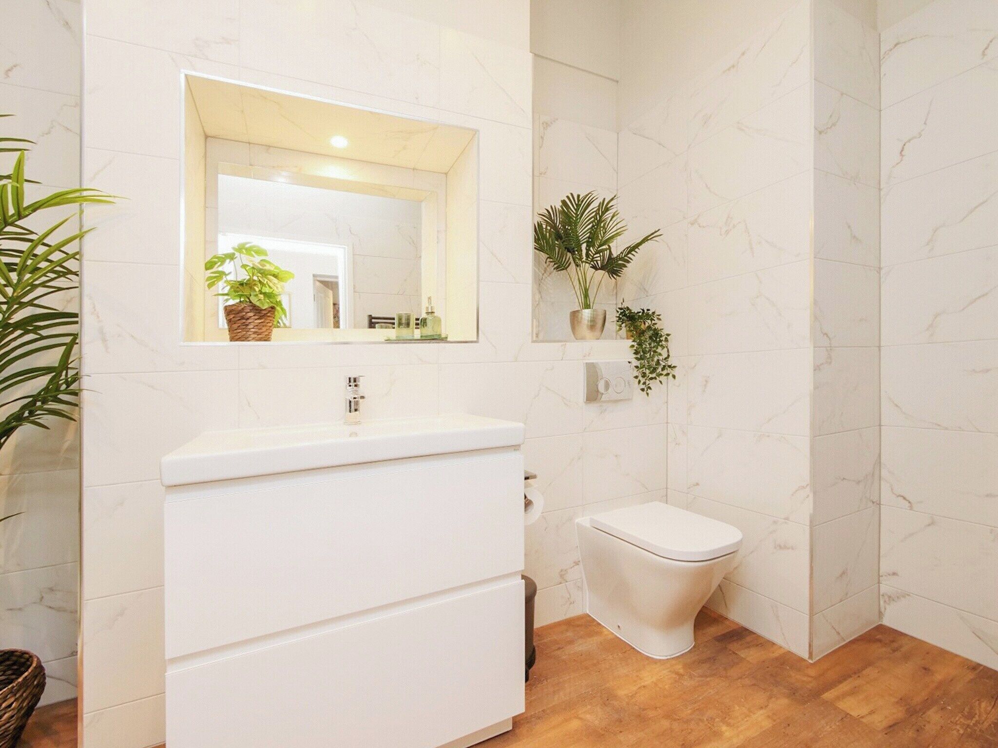 A bathroom with a white vanity, a toilet, and marble walls.