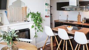 A modern kitchen with a dining area, a clock on the wall, and a plant. - Seaside Apartment-UK2801 (Aberystwyth)