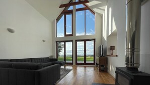 Een moderne woonkamer met een hoekbank, een open haard en een grote schuifdeur met uitzicht op een golfbaan.
