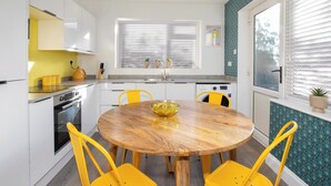 Uma cozinha moderna com armários brancos, uma mesa de jantar amarela e cadeiras amarelas.