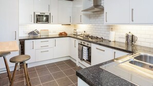 A modern kitchen with white cabinets, a black countertop, a stainless steel sink, and a built-in oven. - 3 bedroom accommodation in York (York)