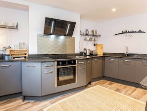 Eine moderne Küche mit grauen Schränken, einem eingebauten Backofen und einer Edelstahl-Dunstabzugshaube.