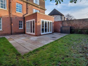 A brick house with a patio, a small fenced garden, and a conservatory with glass doors. - The Presidential Suite (York)