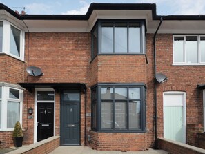 A two-story brick house with a dark-colored front door, a satellite dish on the roof, and a number '21' on the wall. - Wonderful family home ideally located to enjoy a city break in York. (York)