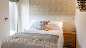 Quarto com uma cama, mesa de cabeceira, relógio de parede e janela com persiana verde.