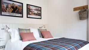 A bed with a plaid blanket, white pillows, and a headboard. Two framed pictures are on the wall above the bed. - 2 bedroom accommodation in Inverness (Inverness)