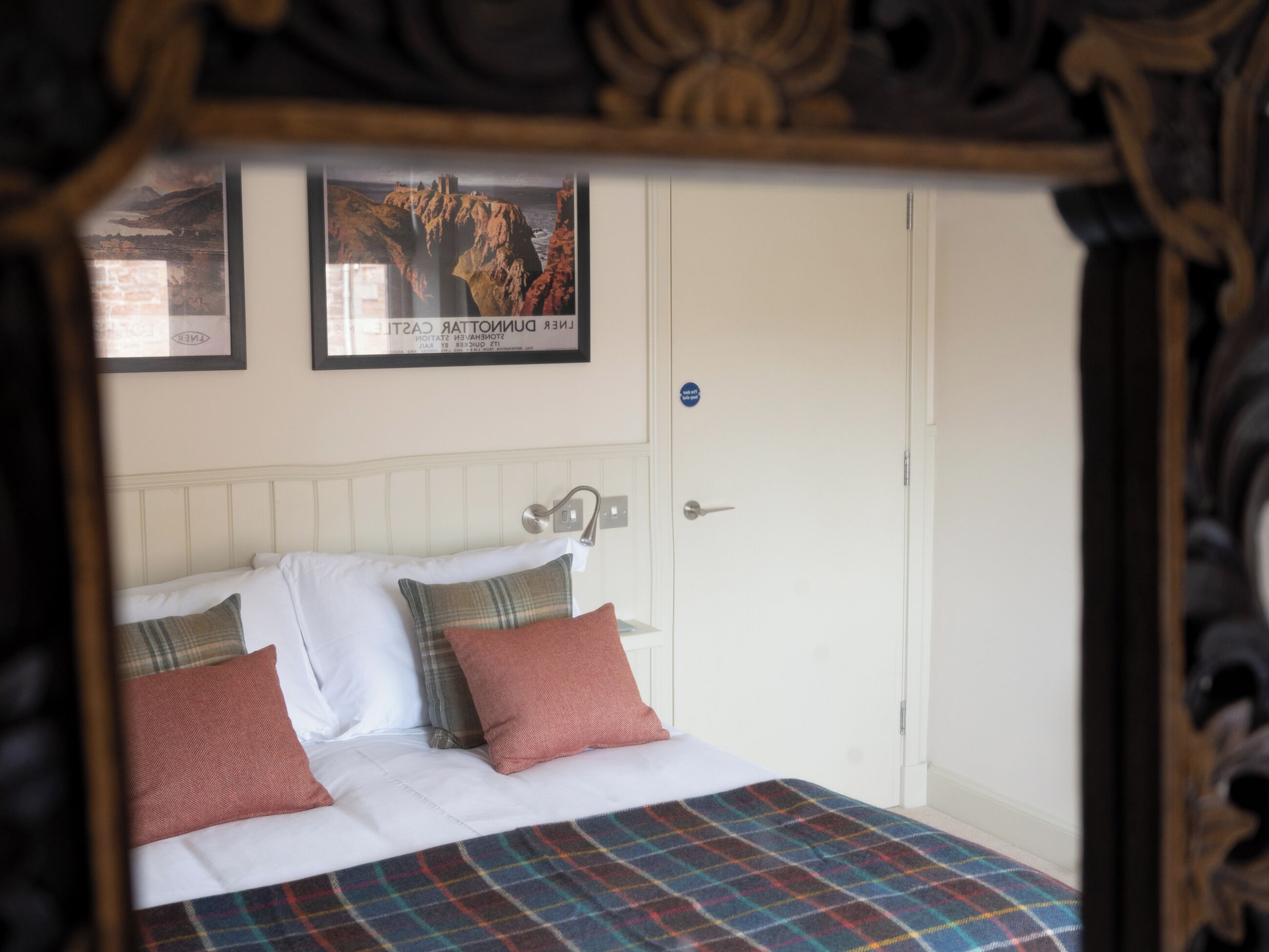 A bedroom with a bed, pillows, a headboard, a door, and a poster on the wall.