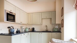 A kitchen with white cabinets, a microwave, a sink, and a toaster. - 2 bedroom accommodation in Inverness (Inverness)