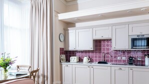 A modern kitchen with white cabinets, a microwave, and a tiled backsplash. - Scottish Thistle - UK7561 (Inverness)
