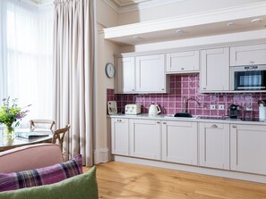 A modern kitchen with white cabinets, a microwave, and a tiled backsplash. - Scottish Thistle - UK7561 (Inverness)