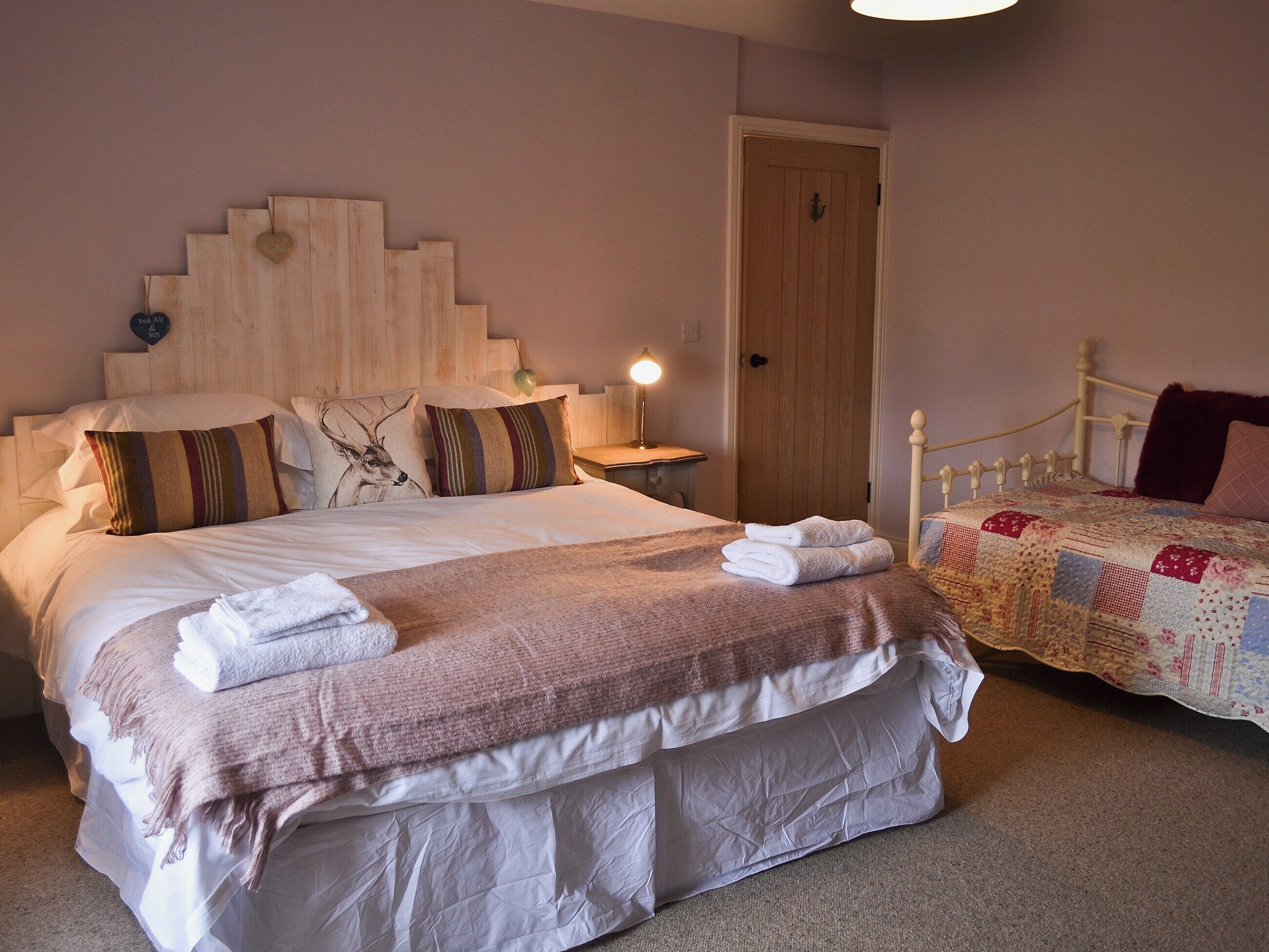 A neatly made bed with a headboard, pillows, and folded towels.