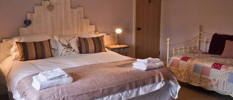 A neatly made bed with a headboard, pillows, and folded towels.