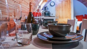 A dining area with a wooden ceiling, a bottle of wine, glasses, and a bowl on a table. - A perfect escape for couples and friends. (Stewarton)