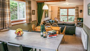 A cozy living room with a sofa, dining table, and chairs. There is a window with curtains, a lamp, and a radiator. - We love this hidden little secret. (Moffat)