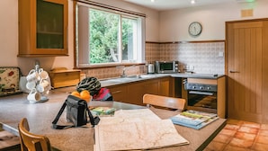 A kitchen with wooden cabinets, a microwave, a kettle, and a dining table with chairs. - We love this hidden little secret. (Moffat)