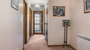 A hallway with a carpeted floor, wooden doors, a radiator, and a framed picture on the wall. - We love this hidden little secret. (Moffat)