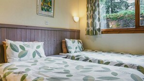 A double bed with leaf-patterned bedding, a wooden headboard, a wall-mounted light, and a window with curtains. - We love this hidden little secret. (Moffat)