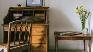 A wooden desk with drawers, a chair, a lamp, a framed picture, and a vase with flowers. - Clachan Annex - UK7626 (Pitlochry)