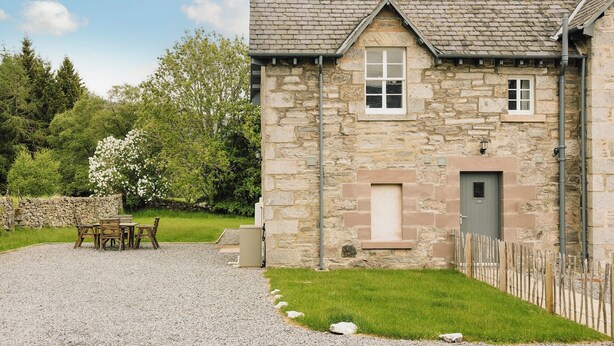 A stone building with a gravel driveway, a wooden fence, and a grassy area with a bench. - Clachan Annex - UK7626 (Pitlochry)