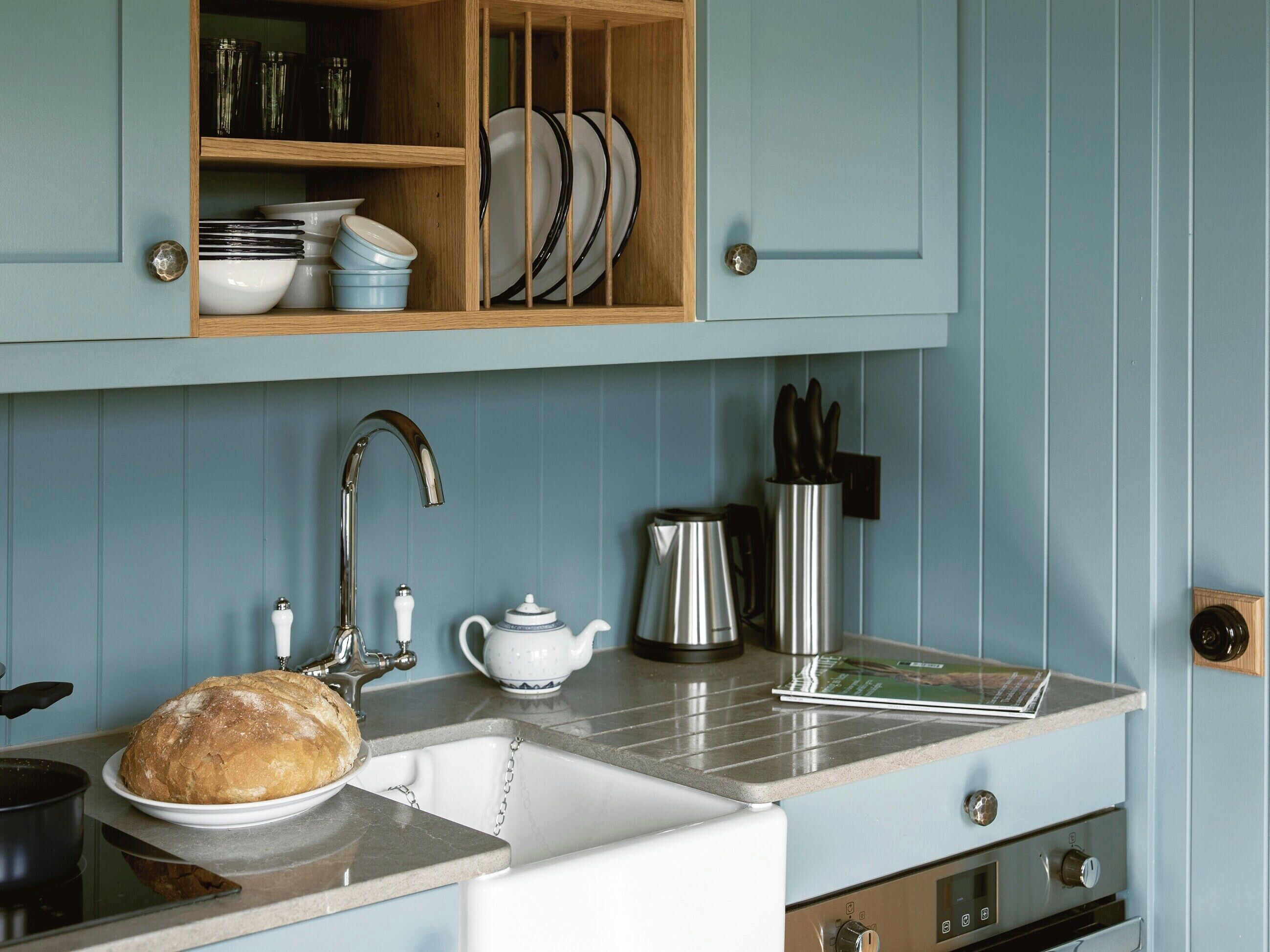 A kitchen with a sink, a loaf of bread, a kettle, and a coffee pot on the counter.