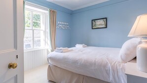 Ein Schlafzimmer mit Bett, Fenster, Gemälde und Lampe.