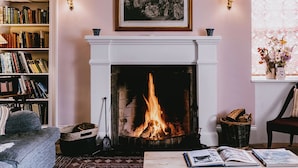 A cozy living room with a fireplace, bookshelves, a comfortable sofa, and a table with books.