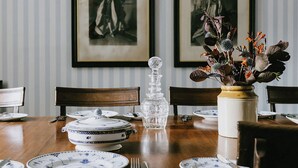 A dining table set with plates, a crystal decanter, and a floral arrangement.