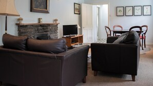 A living room with a stone fireplace, a television, and a dining area with chairs and a table. - Marble Lodge - UK7635 (Pitlochry)