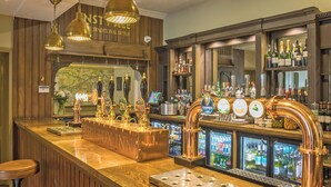 Een bar met verschillende biertaps, een kassa en een assortiment drankflessen.